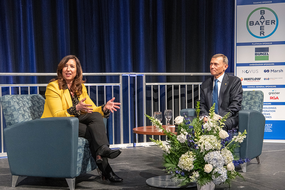 Christine Duffy, President of Carnical Cruises, discusses gestures to the audience while seated on stage during a discussion with moderator Gene Cunningham at the 2021 Bayer International Business Conference presented by the Boeing Institute of International Business at Saint Louis University's Chaifetz School of Business.