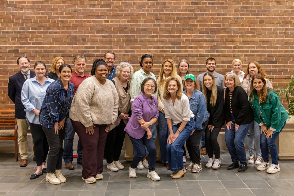 group of people smiling and posing in front a brick wall
