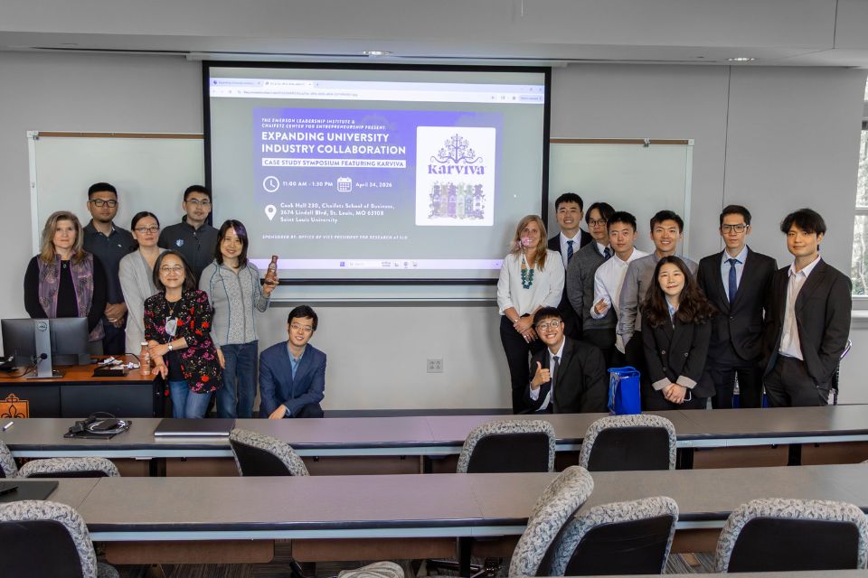 a group of people stand posed on either side of a projector screen