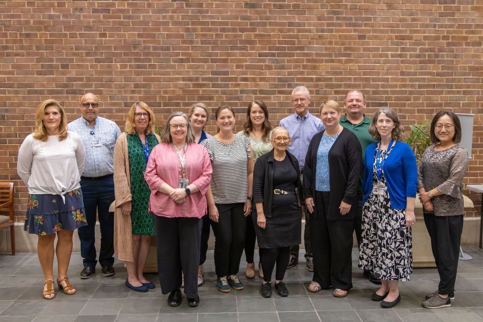 group of people smiling and posing in front of a brick wall