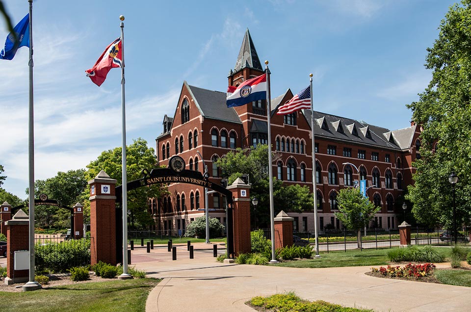 SLU's DuBourg Hall, seen from across Grand Boulevard with flags flying in the foreground.
