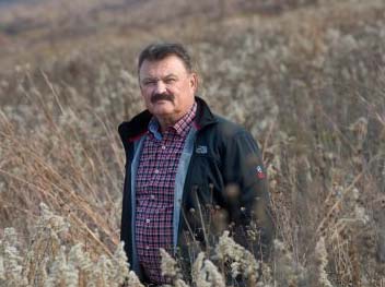 Rudi Roeslein stands in a field of waist-high grasses.