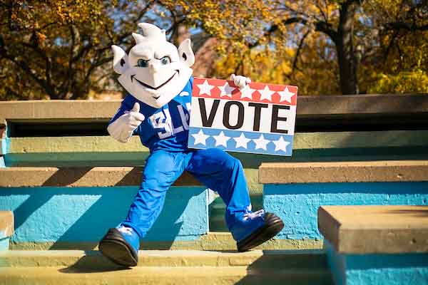 Billiken mascot holding sign reading "vote."
