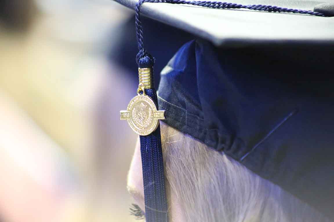 A graduating student in ceremonial cap and gown at campus commencement