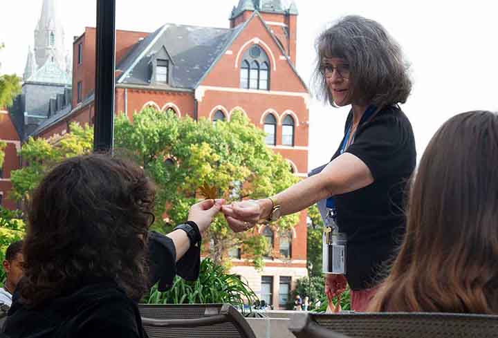 A teacher with Dubourg Hall in the background touches hands with a student
