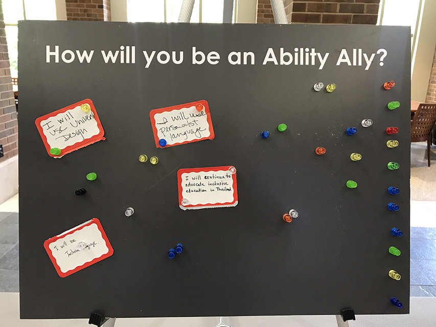 Sign reading "How Will You be an Ability Ally" Answers posted include "I will use people first language," "I will use inclusive design" and "I will continue to advocate for inclusive education in Thailand"