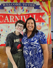 Two participants pose in front of a sign that reads Welcome to the Carnival.
