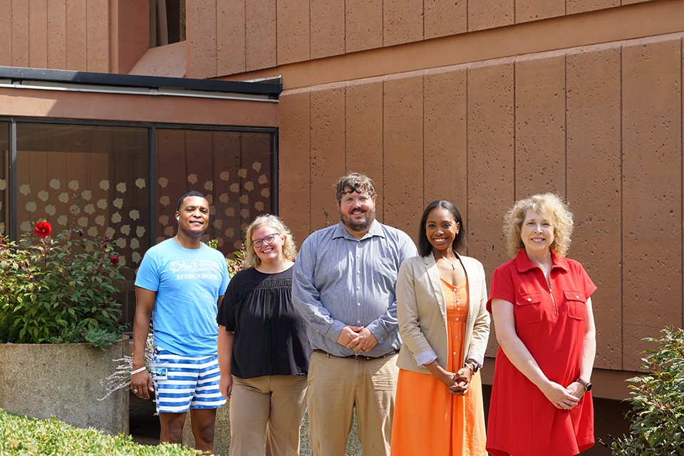 Five faculty members pose in a line outside on the SLU campus.