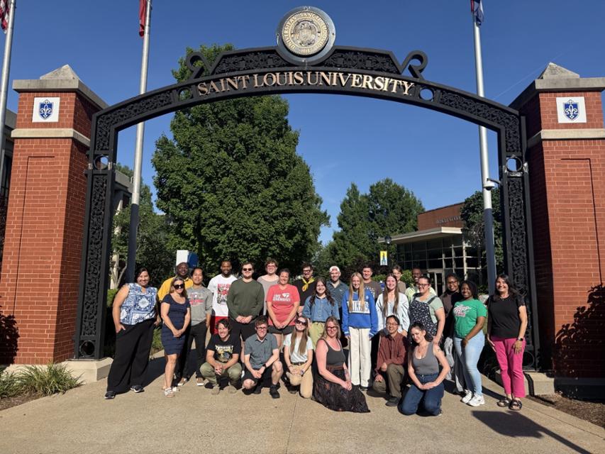A group of STL Teaching Fellows pose in front of the SLU pedestrian arch