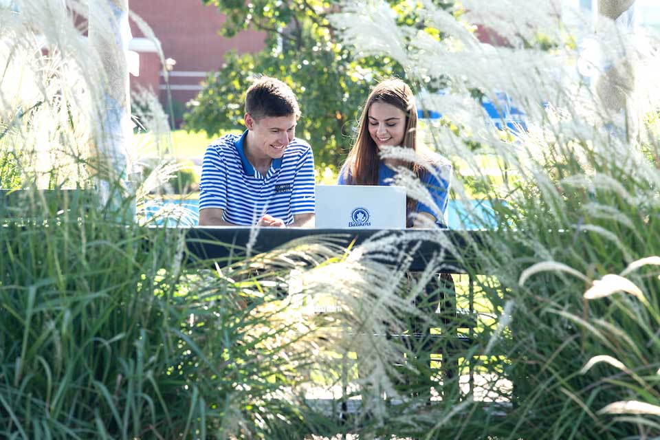 Two students at laptop in a gazebo