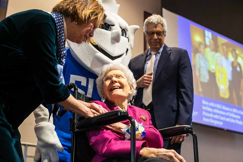 Mary's 100th Birthday Dr Fran Pestello holds Mary Bruemmer's hand at her 100th birthday celebration while the Billiken and Dr Fred Petesllo look on
