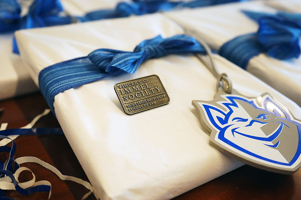 A wrapped gift sits on a table with a pin that says Vincent C. Immel Society.