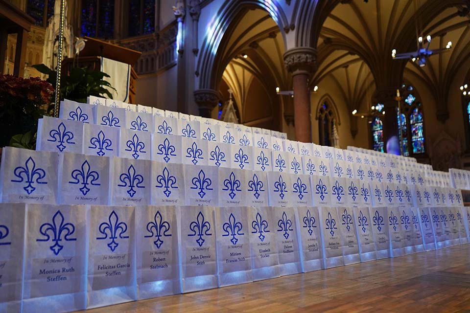 Luminaries with names on them line the steps inside a church.
