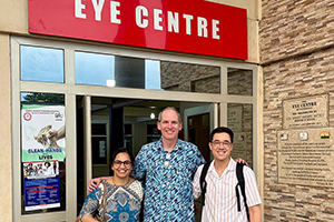 Michael Brush, M.D., poses for a photo with two others outside of a building with a sign that says Eye Centre.