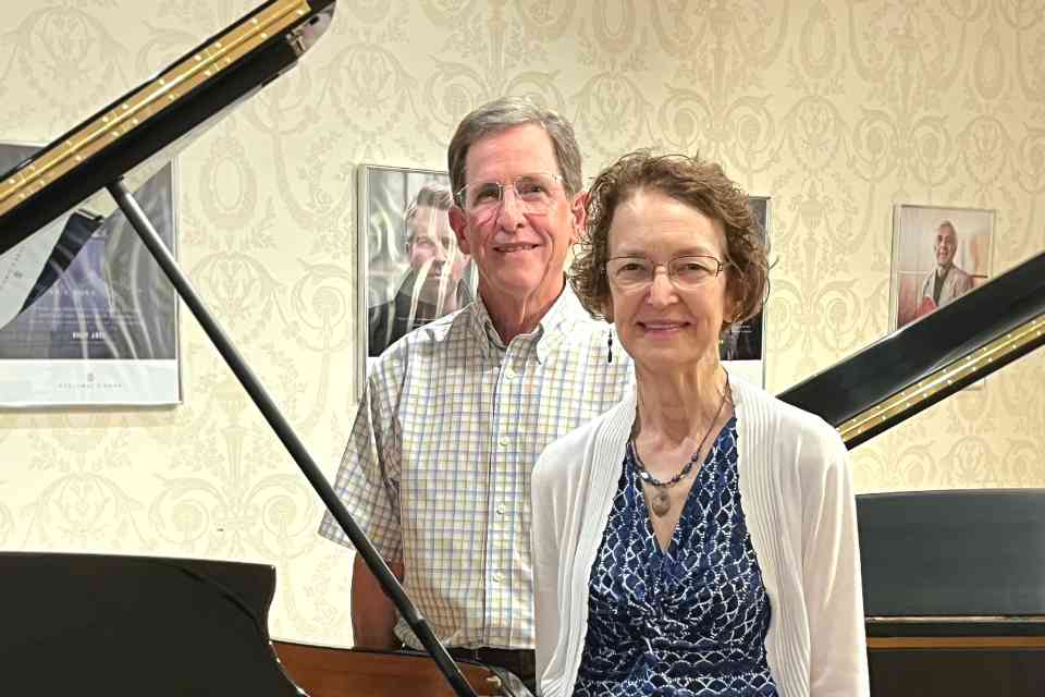 Tom and Kathy Day stand in front of piano in the Steinway showroom