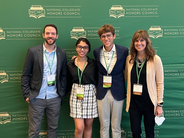 Four students posed for a picture against a wall at the NCHC conference