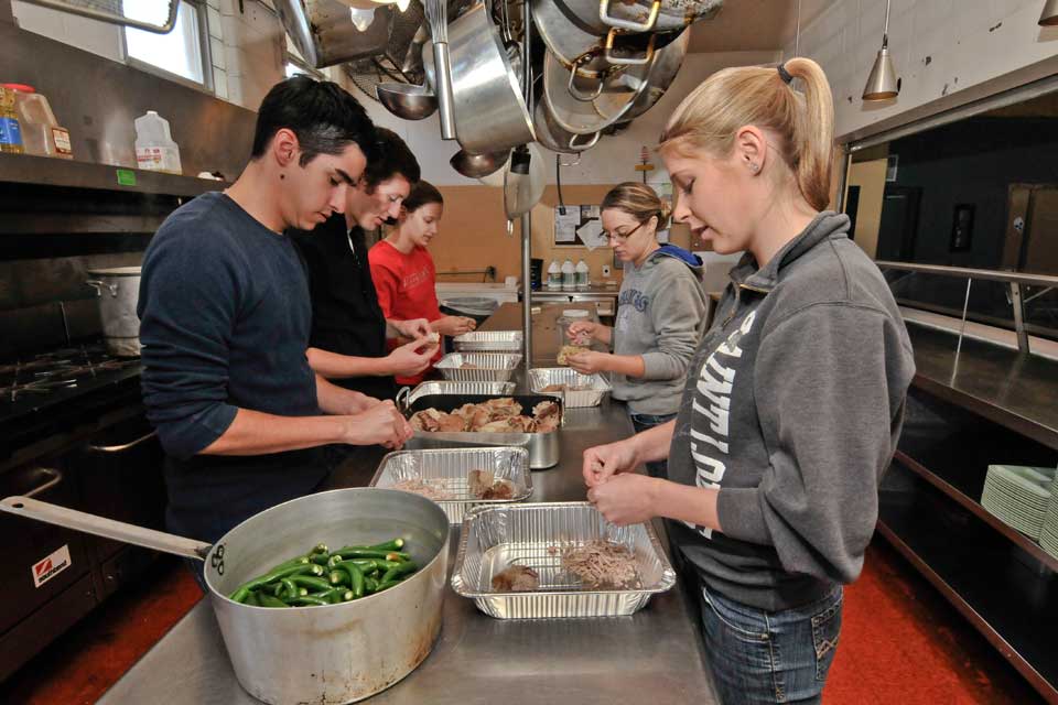 Students in a row volunteering at a food kitchen