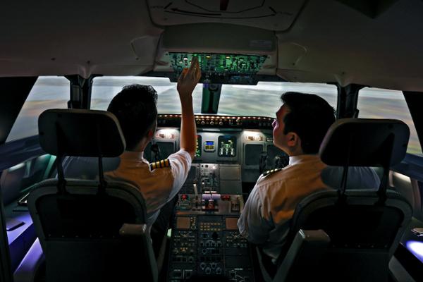 Two students in a flight simulator pictured from behind