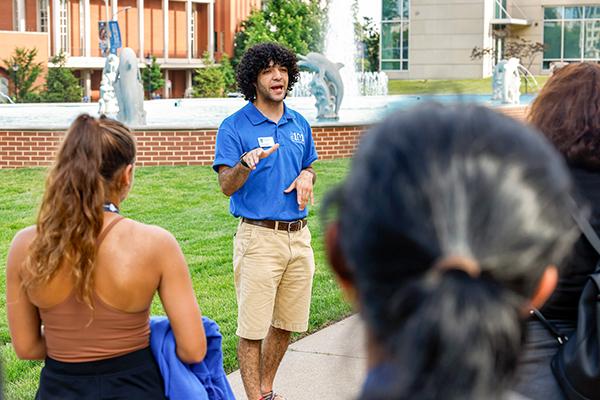 A SLU campus ambassador gives a tour to prospective families in front of the dolphin pond