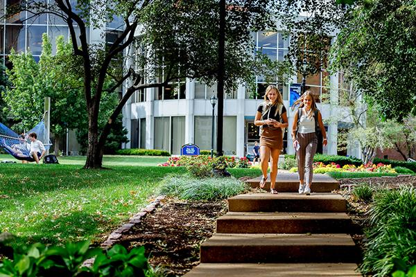 Two students walking down the steps with Pius Library in the background