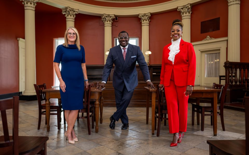 Jen Crompton, Trez Quinn, and Monique Abby pose in the courtroom at the Old Courthouse in downtown St. Louis.