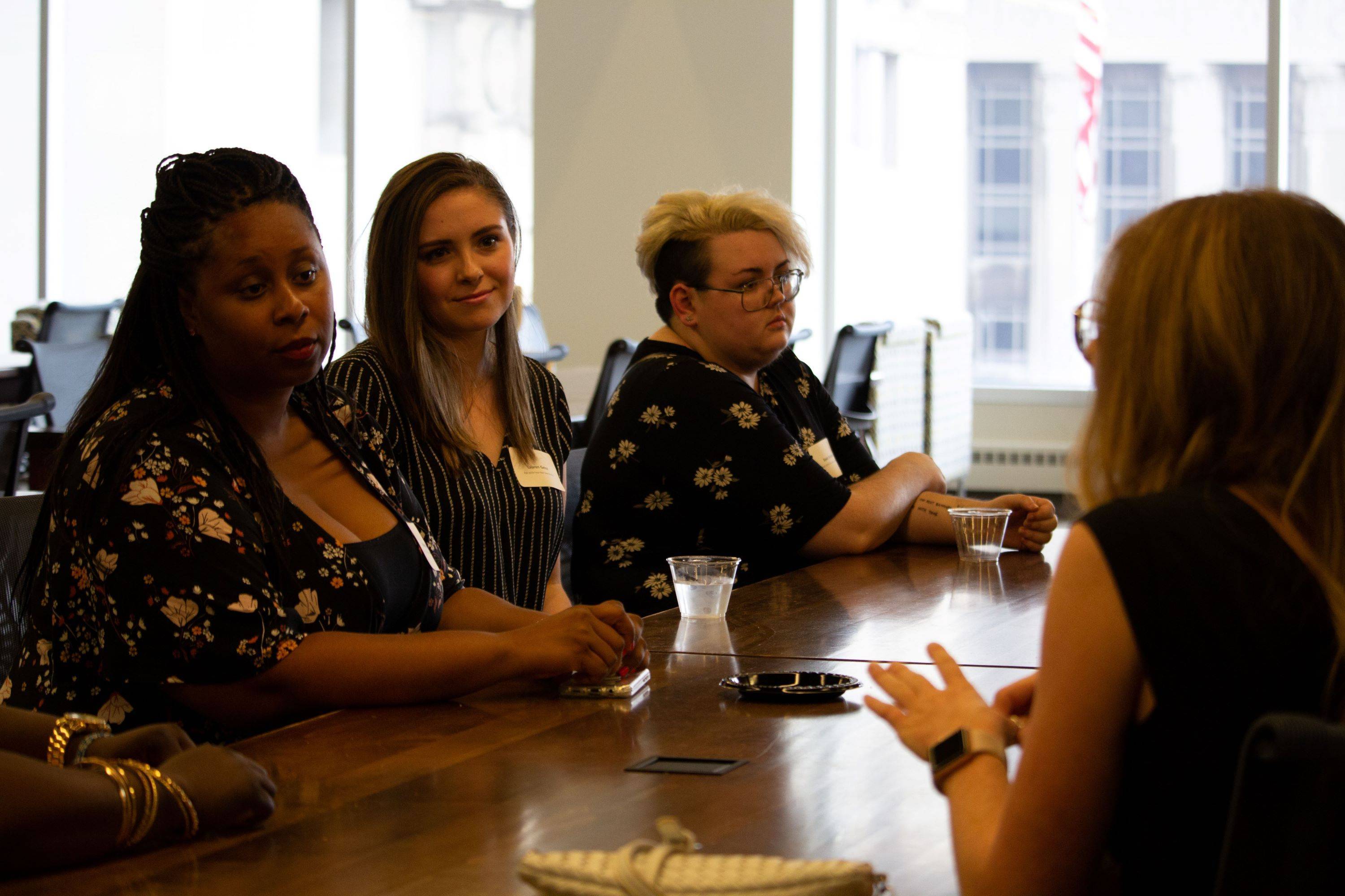 Four women have a discussion while sitting at a table.