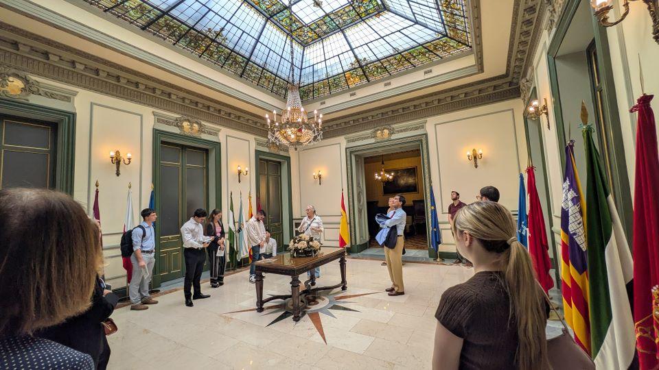Students visit the Madrid Supreme Court Visitors stand during a tour in a room in the court building with a stained glass ceiling.