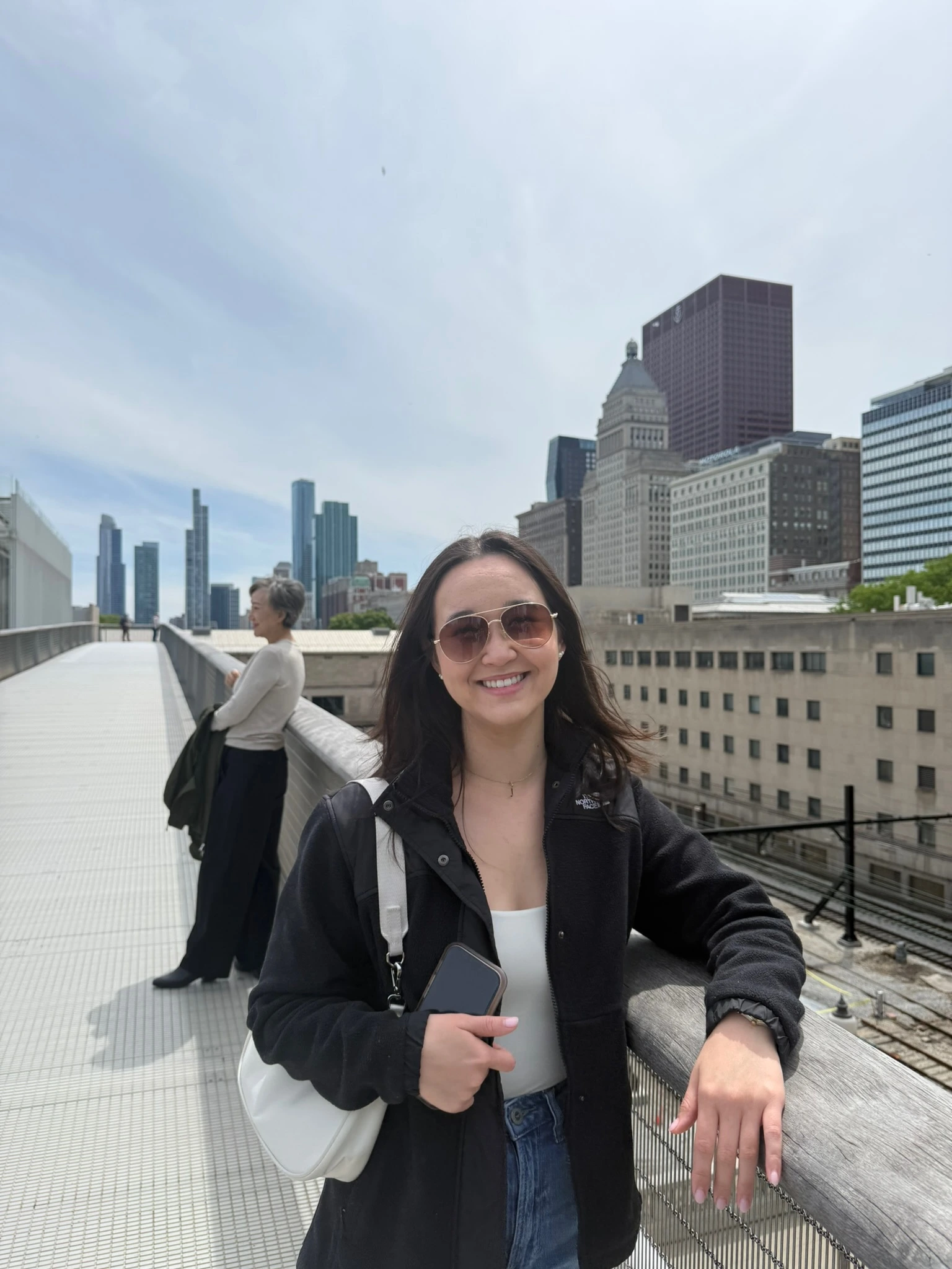 Amanda smiling on a bridge with a city skyline behind her.