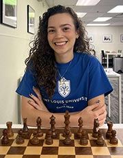 Gabriela Feller poses for a photo while sitting in front of a chess board