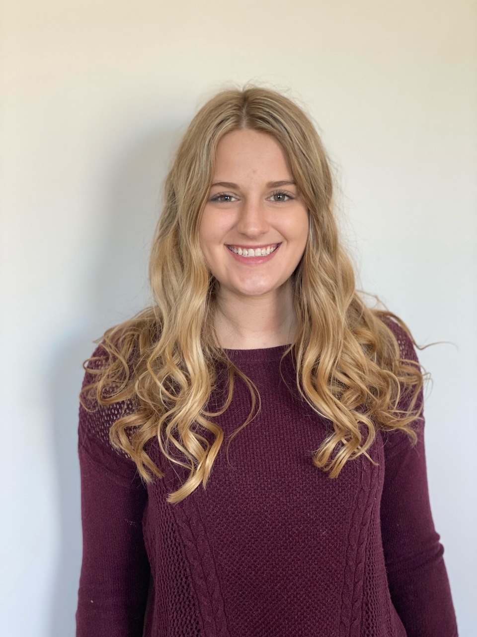 Emma Winningham Picture A white woman with blonde hair smiling in a maroon shirt.