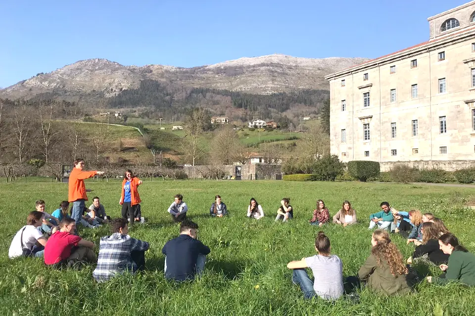 Students sit in a circle in a field.