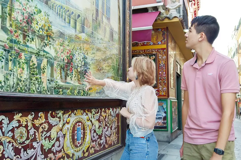 Two students looking at a painting on a wall.