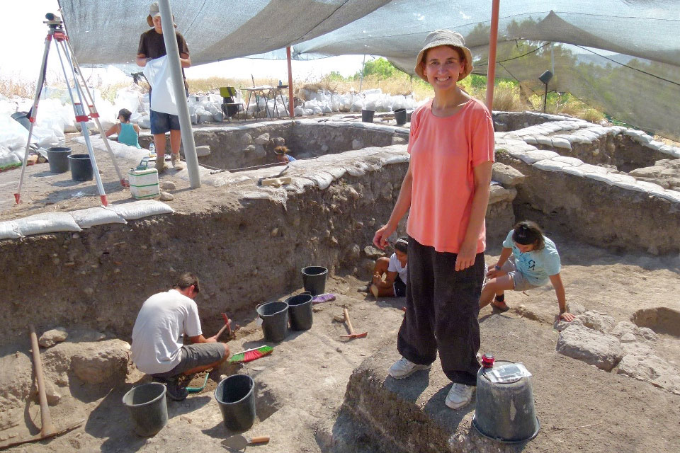Carolina Aznar, Ph.D., at the site of the excavation in 2013. She stands at the center of the dig, wearing a pink shirt, dark pants and a beige hat. Other team members are at work around her. Photo provided by Carolina Aznar.