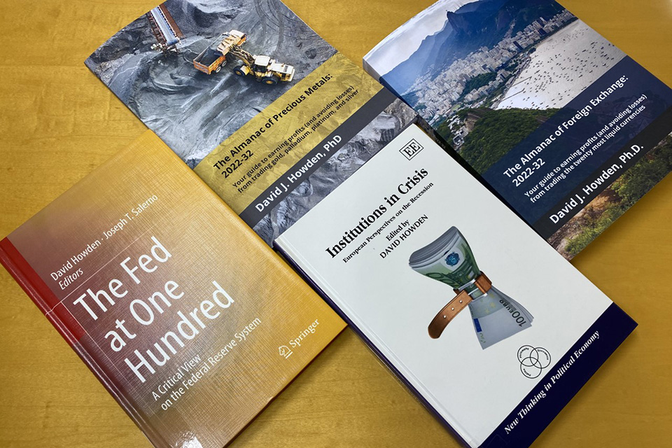 Four books authored by Dr. Dave Howden at SLU-Madrid are displayed on a table.
