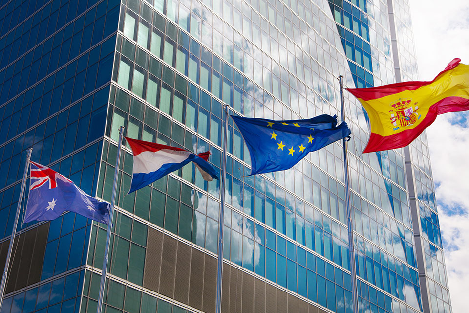 The flags of Australia, Netherlands, European Union and Spain fly outside of an office building, symbolizing the international success of SLU Madrid graduates.