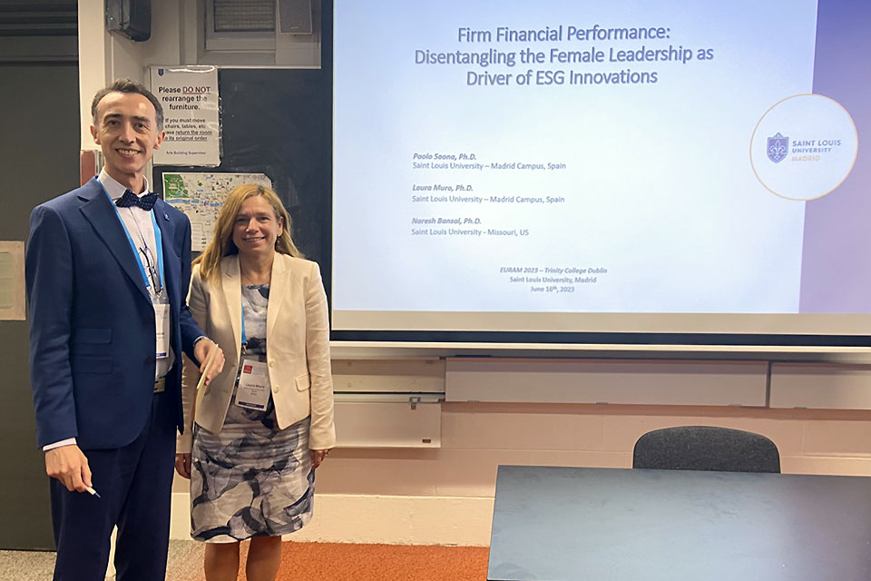 Two facult members pose next to a presentation screen reading "Firm Financial Performance: Disentangling the Female Leadership as Driver of ESG Innovations"