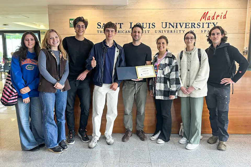 A group of people posing for a photo while the man  in the middle holds a certificate.