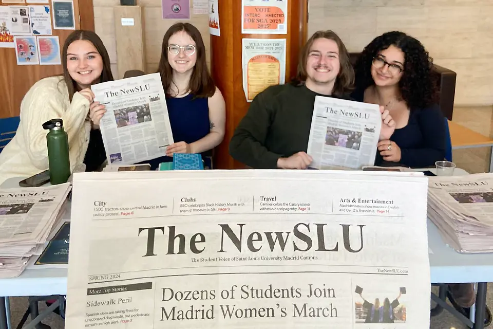 Newspaper held up to camera with four students smiling and holding up newspapers.