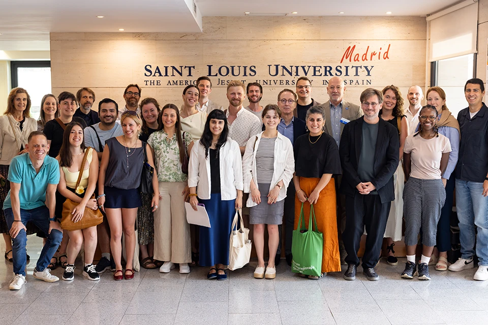 Participants pose for photo in San Ignacio Hall reception. People smile at camera and pose for group photo with University logo behind them on the wall.