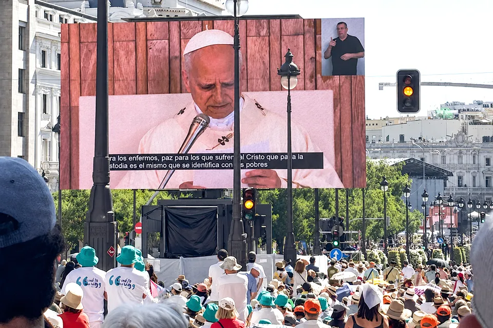 SLU-Madrid Community Reflects on Pope Leo XIV's Historic Visit to Spain A large crowd of faithful fills the streets of downtown Madrid during the Pope's visit as they watch a large screen showing his image.