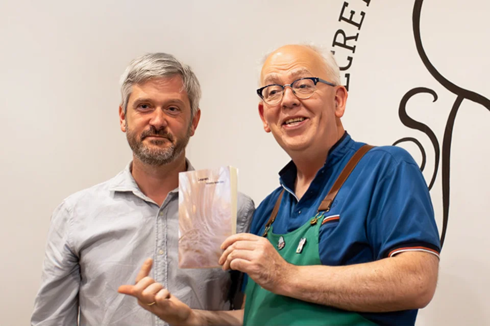 SLU-Madrid Professor Timothy Ryan Day Releases New Novel "Leaven" Two men stand while holding up a book.