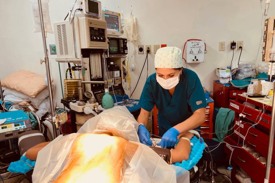 Weber A doctor wearing scrubs, gloves and a surgical mask bends over a patient in an operating room