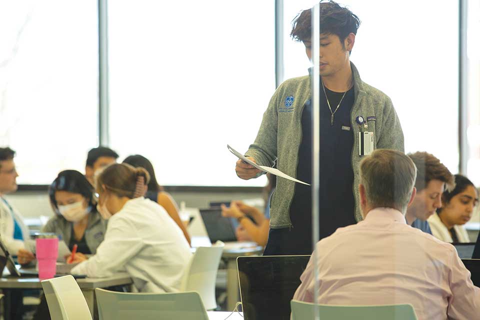 Student standing and reading a paper he wrote to the class