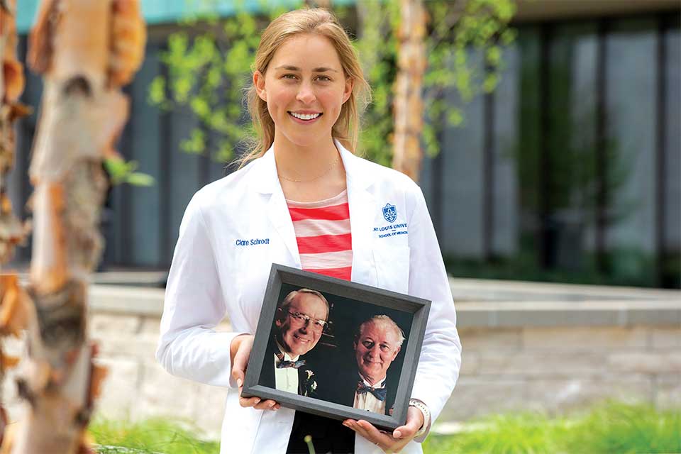 Picture of Clare Schrodt holding a photo of her previous family members that attended SLU School of Medicine