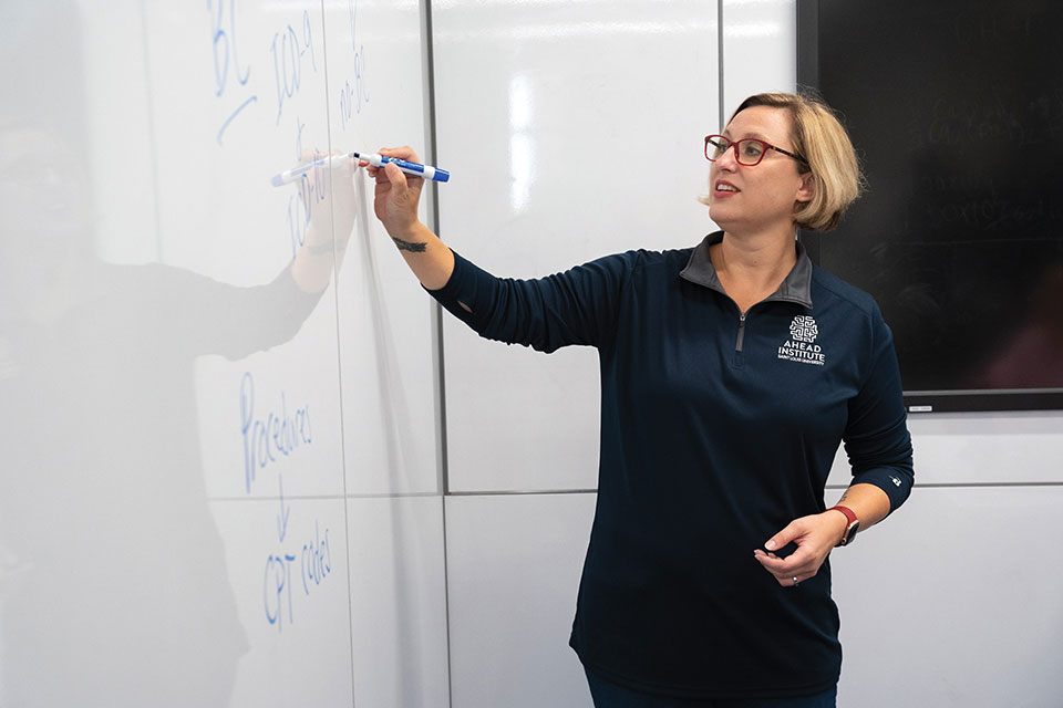 AHEAD researcher Leslie Hinyard instructs students in front of a white board