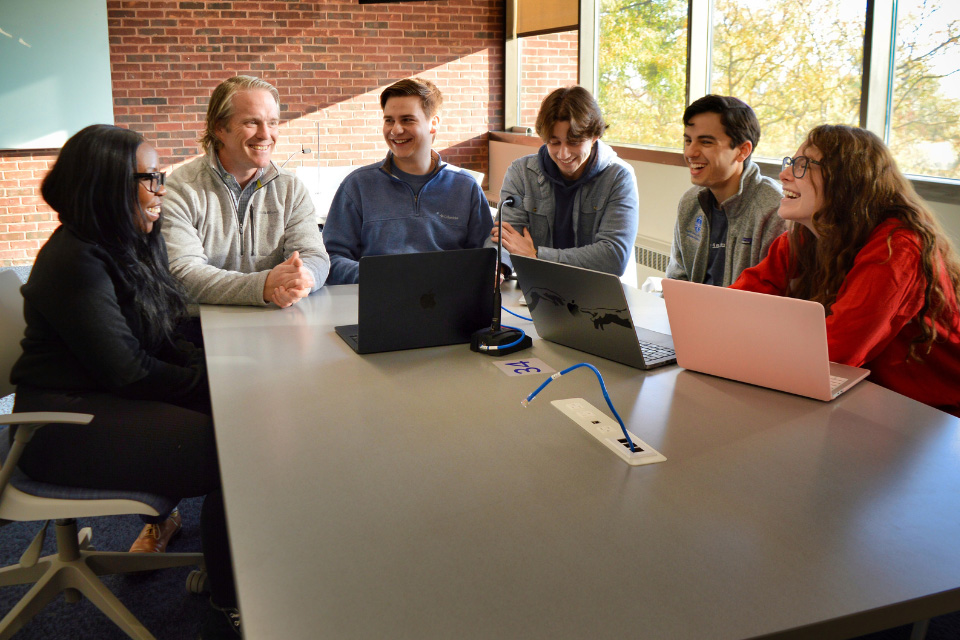 Group of students gathered around a table discussing and studying together