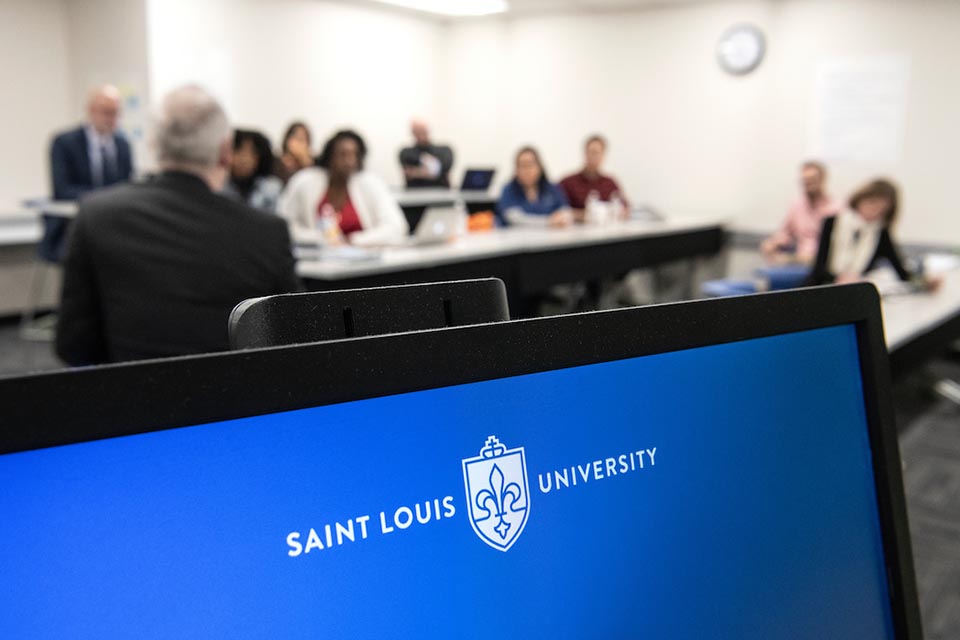 Saint Louis University classroom with laptop in focus and students in background