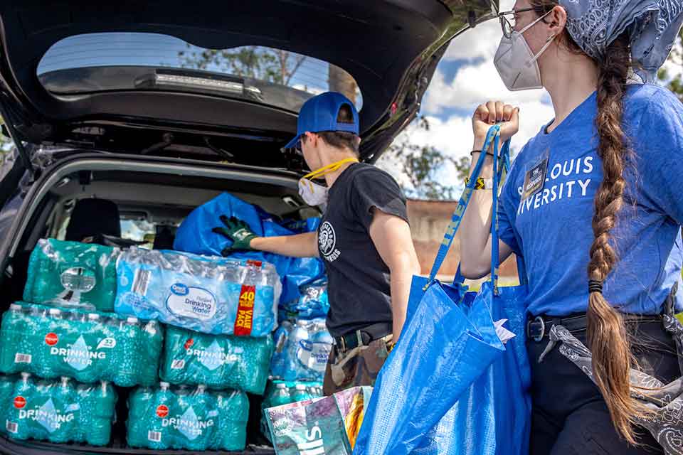 Two students loading supplies into a vehicle Two students loading supplies into a vehicle