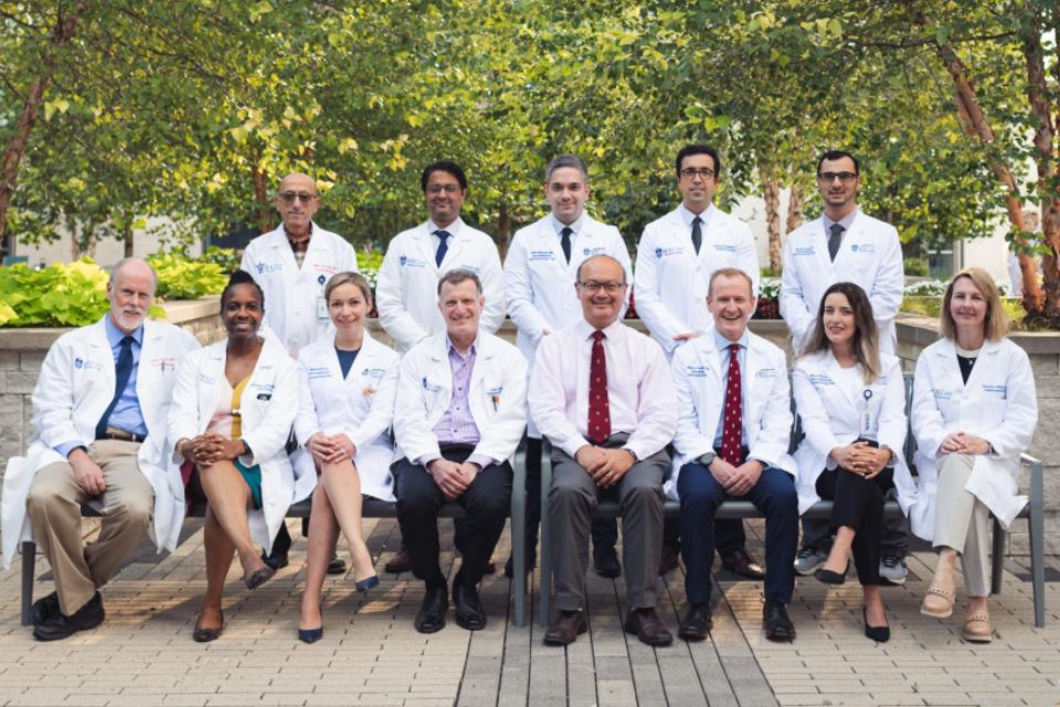 A group portrait of gastroenterology and hepatology faculty sitting on benches in front of trees.
