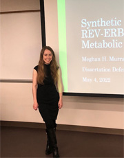 meghan-murray-defense Picture of Meghan Murrany standing infron of a screen projection with her dissertain defense presentation